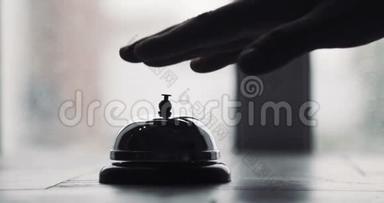男子按响酒店接待铃，男子按动住宿电话铃在木制接待前台。